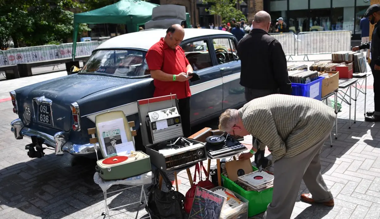 Pelanggan melihat-lihat setumpuk piringan hitam di Classic Car Boot Sale, London, Inggris, 7 Agustus 2021. Classic Car Boot Sale berlangsung selama dua hari. (JUSTIN TALLIS/AFP)