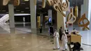 Warga Saudi berjalan di bawah guntingan huruf Arab yang menghiasi Pusat Kebudayaan Dunia Raja Abdulaziz, juga dikenal sebagai Ithra, di Dammam, Arab Saudi, Minggu (27/6/2021).  Pusat ini dibangun oleh Saudi Aramco dan diresmikan oleh Raja Salman pada 2016. (AP Photo/Amr Nabil)