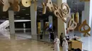 Warga Saudi berjalan di bawah guntingan huruf Arab yang menghiasi Pusat Kebudayaan Dunia Raja Abdulaziz, juga dikenal sebagai Ithra, di Dammam, Arab Saudi, Minggu (27/6/2021).  Pusat ini dibangun oleh Saudi Aramco dan diresmikan oleh Raja Salman pada 2016. (AP Photo/Amr Nabil)