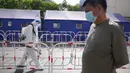 <p>Seorang warga mengantre untuk tes COVID-19 saat seorang pekerja mendisinfeksi pembatas di Beijing, China, Selasa (3/5/2022). China telah berpegang teguh pada pendekatan ketat 'Nol COVID' yang membatasi perjalanan, menguji massal seluruh kota, dan mendirikan fasilitas sementara yang luas untuk mencoba mengisolasi setiap orang yang terinfeksi. (AP Photo/Ng Han Guan)</p>