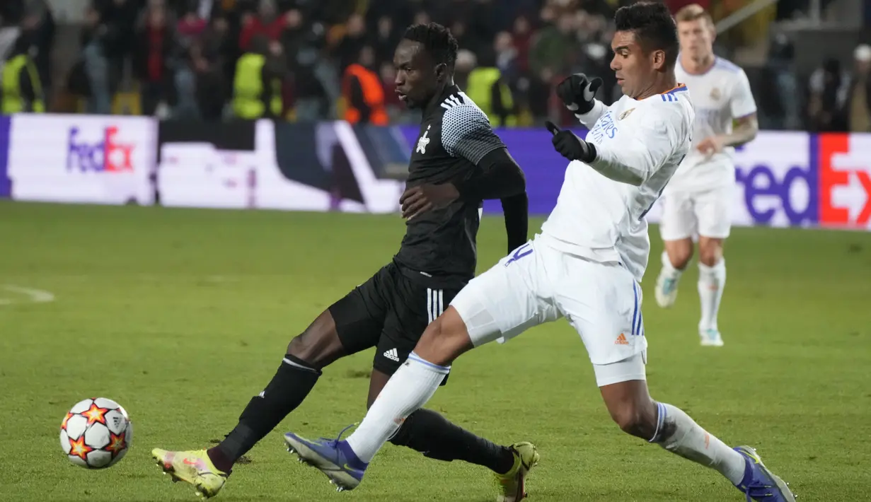 Gelandang Real Madrid Casemiro berebut bola dengan penyerang Sheriff Tiraspol Adama Traore dalam laga matchday 5 fase grup Liga Champions 2021/22 di Bolshaya Sportivnaya Arena, Kamis (25/11/2021) dini hari WIB. Real Madrid sukses menghajar Sheriff Tiraspol dengan skor 3-0. (AP Photo/Sergei Grits)