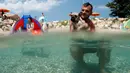 Seorang pria berenang bersama anjingnya di pantai anjing dan bar di Crikvenica, Kroasia, (12/7). Pantai dan bar ini dirancang khusus untuk para anjing dan pemiliknya demi merasakan kenikmatan Summertime bersama-sama. (REUTERS/Antonio Bronic)