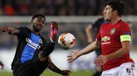 Striker Club Brugge Emmanuel Dennis (kiri) coba melewati bek Manchester United (MU) Harry Maguire pada leg pertama babak 32 besar Liga Europa di Jan Breydel Stadium, Kamis (20/2/2020) atau Jumat dini hari WIB. (AFP/Adrian Dennis)