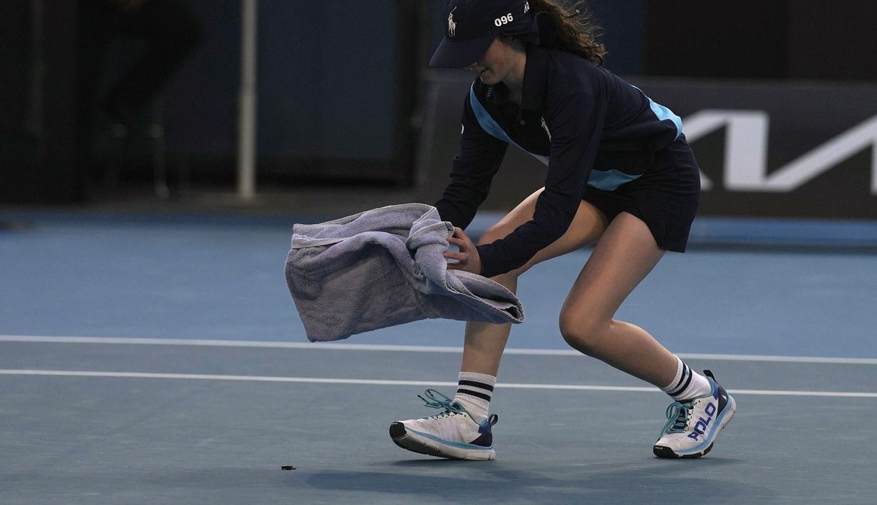 Seorang ball girl berusaha menangkap seekor serangga yang memasuki lapangan menggunakan handuk ketika laga Australia Open 2024 antara petenis Inggris, Emma Raducanu melawan petenis Amerika Serikat di Melbourne Park, Melbourne, Australia, Selasa (16/01/2024). (AP Photo/Louise Delmotte)