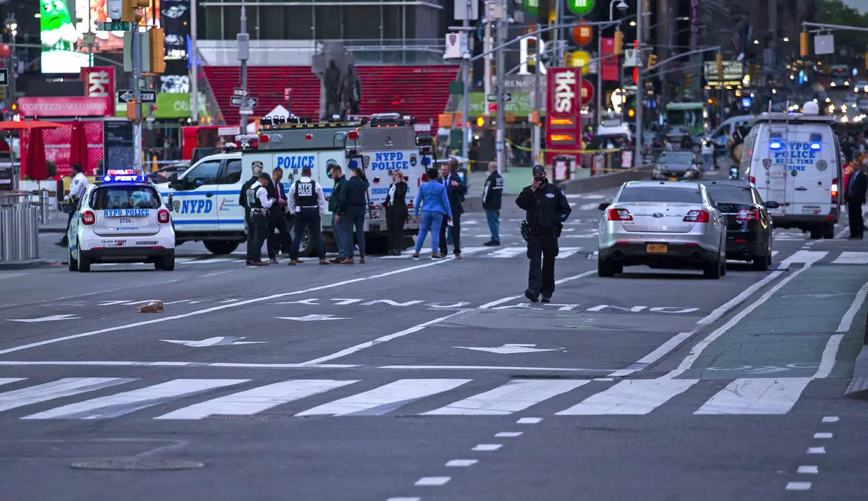 Petugas polisi terlihat sedang melakukan pemeriksaan di lokasi penembakan di Times Square di New York, AS (8/5/2021). Menurut laporan, tiga orang, termasuk seorang balita terluka dalam penembakan itu. (AFP/Kena Betancur)