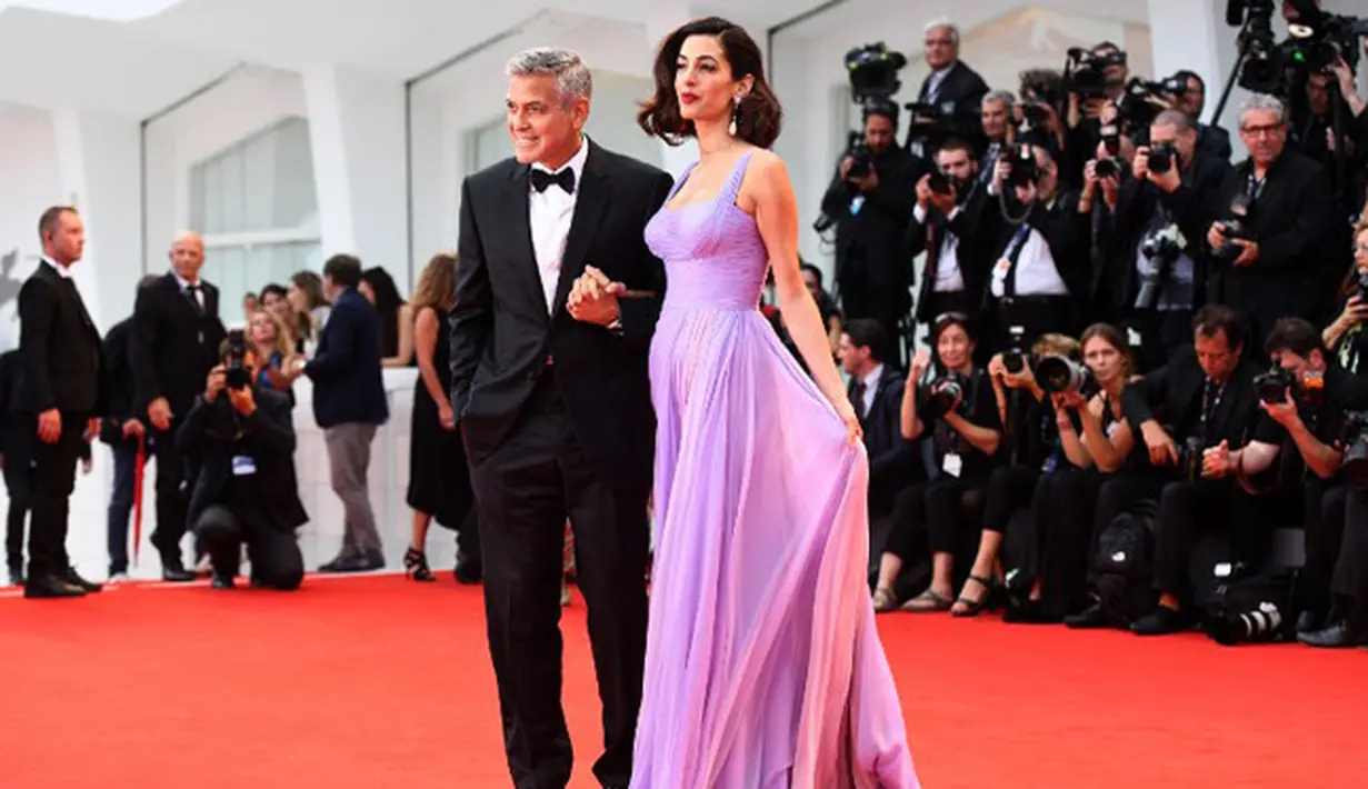 George Clooney dan Amal Clooney, salah satu pasangan selebriti Hollywood yang tak malu memamerkan kemesraannya di depan publik. Namun keduanya sempat tak terlihat sejak kelahiran anak kembar mereka. (AFP/Tiziana Fabi)