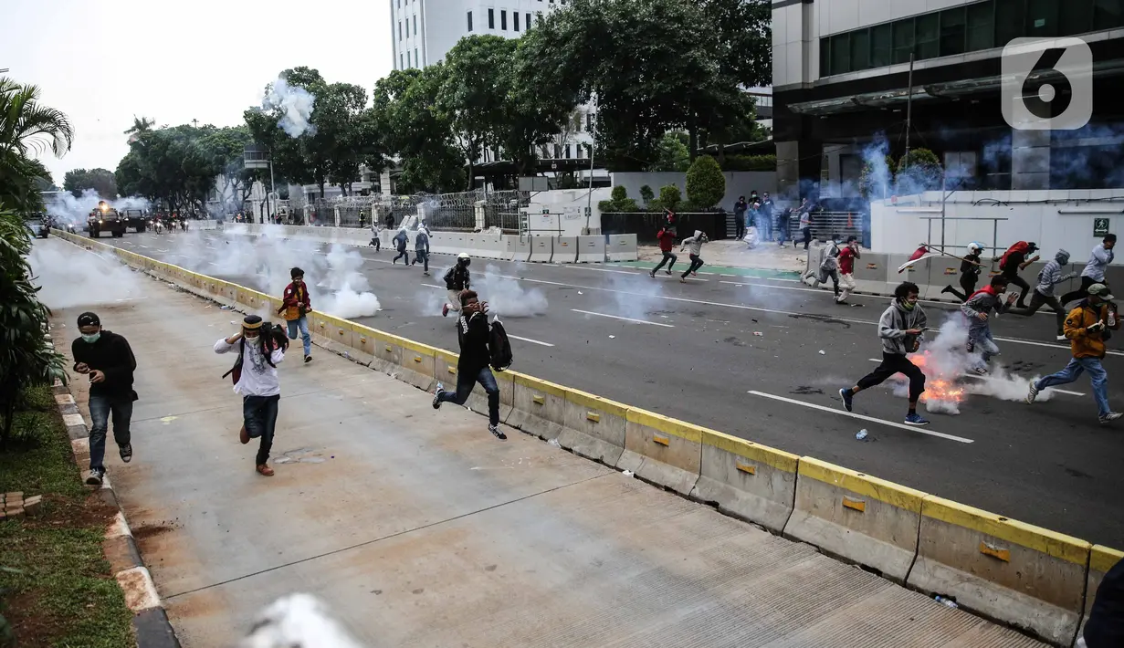 Pengunjuk rasa tolak UU Cipta Kerja bentrok dengan polisi di sekitar Patung Kuda, Jakarta Pusat, Selasa (13/10/2020). Gas air mata ditembakkan ke arah pendemo yang melakukan perlawanan dengan melempar batu dan pecahan kaca. (Liputan6.com/Faizal Fanani)