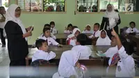 Dua guru mendampingi murid yang mengikuti aktivitas belajar mengajar di SDN Jatinegara Kaum 15 Pagi, Jakarta, Senin (15/7/2019). Sebanyak 32 anak menjadi murid baru SDN tersebut pada hari pertama masuk sekolah tahun ajaran 2019/2020. (merdeka.com/Iqbal S Nugroho)