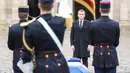 Presiden Prancis Emmanuel Macron  berdiri di dekat peti Letnan Kolonel Arnaud Beltrame dalam upacara nasional di Hotel des Invalides, Paris, Rabu (28/3). Macron memberikan penghargaan perwira tertinggi bagi Beltrame, Legiun d'Honneur. (AP/Christophe Ena)