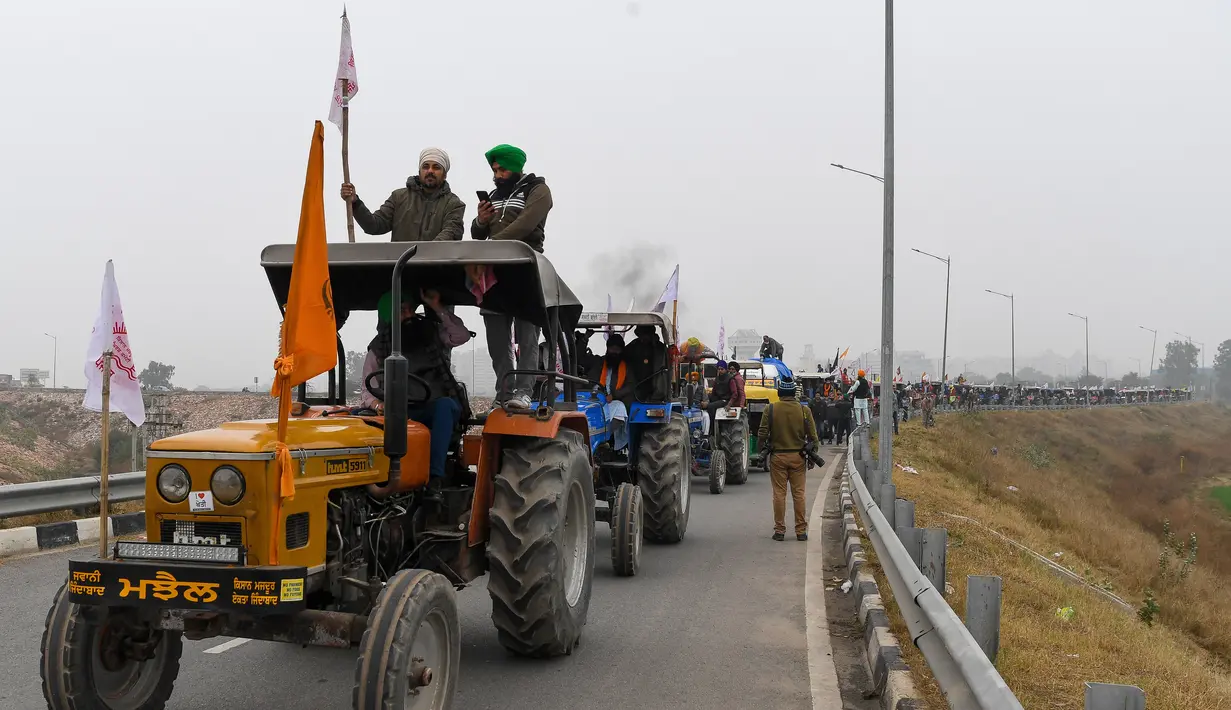Para petani menaiki traktor berpartisipasi dalam unjuk rasa di Jalan Tol Kundli – Manesar – Palwal (KMP) di Kundli di negara bagian Haryana (7/1/2021). Reli traktor kemungkinan akan mempengaruhi lalu lintas di dalam dan sekitar New Delhi. (AFP/Prakash Singh)