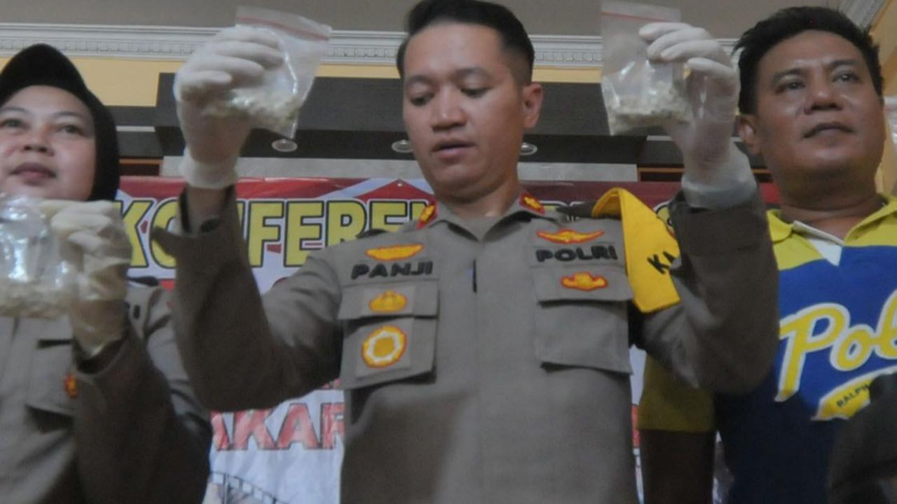 Kapolsek Cakung Kompol Panji Ali Chandra didampingi jajarannya menunjukkan barang bukti ratusan butir pil ekstasi yang diamankan dari tersangka PCR alias Adit dalam rilis kasus peredaran narkoba di Polsek Cakung, Jakarta, Jumat (14/6/2024). Merdeka.com/I