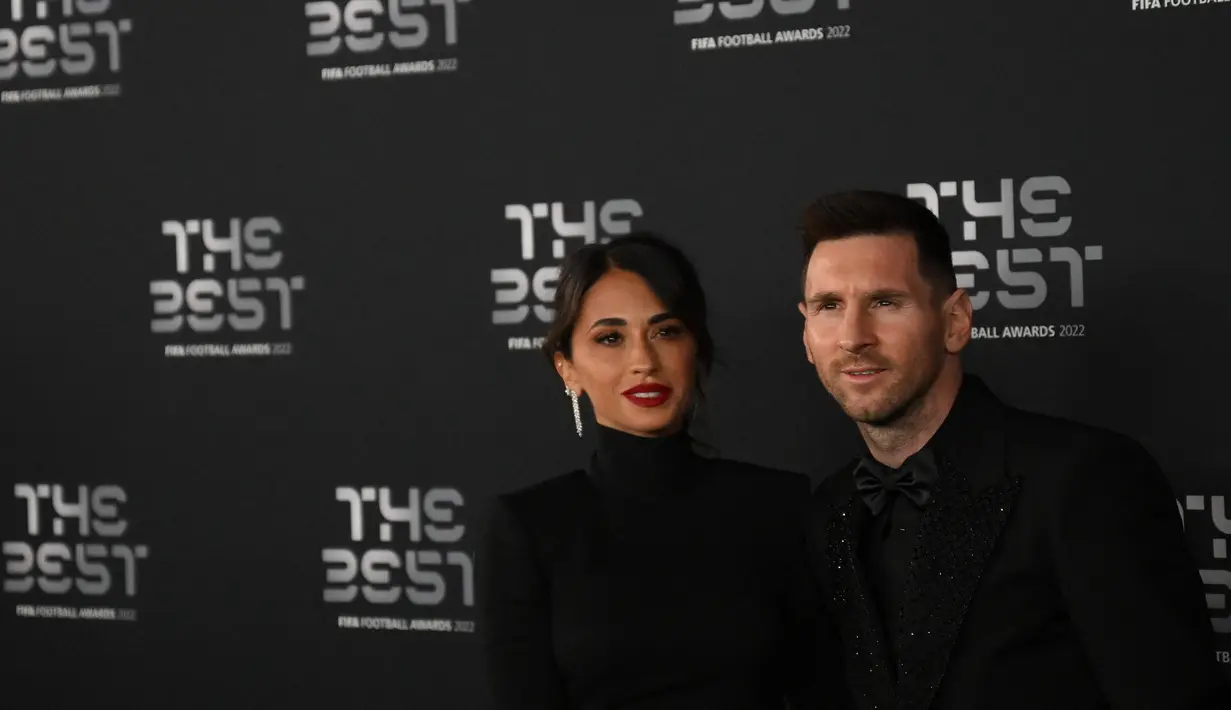 Penyerang Argentina dan Paris Saint-Germain Lionel Messi (kanan) dan istrinya Antonela Roccuzzo berpose setibanya untuk menghadiri ajang The Best FIFA Football Awards 2022 di Paris, Prancis, Senin (27/2/2023). (Photo by FRANCK FIFE / AFP)