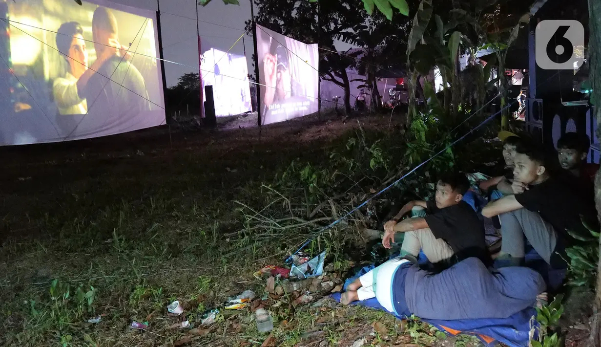 Sejumlah anak tanpa mengenakan masker menonton film layar tancap di kawasan Sawangan, Depok, Jawa Barat, Sabtu (11/7/2020). Layar tancap atau bioskop terbuka menjadi alternatif bagi warga untuk menikmati film di tengah penerapan new normal di kawasan Jabodetabek. (Liputan6.com/Herman Zakharia)