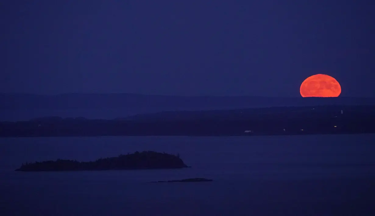 Supermoon terbit di belakang Isle Au Haut di kejauhan, dan Pulau North Haven, bagian tengah, Selasa, 1 Agustus 2023, seperti yang terlihat dari Camden, Maine. Fenomena supermoon 1 Agustus 2023 ini merupakan supermoon kedua dari empat supermoon yang terjadi pada musim panas tahun ini. (AP Photo/Robert F. Bukaty)
