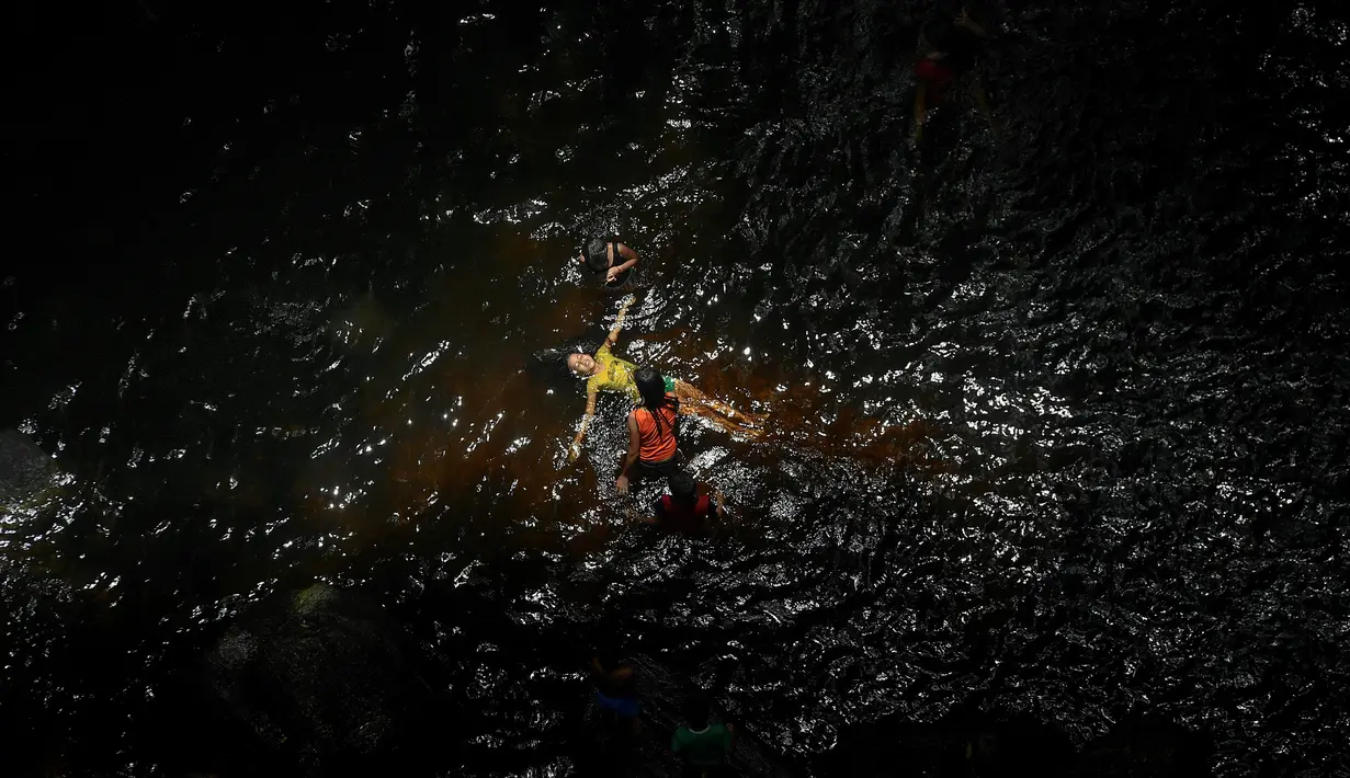 Seorang gadis mengapung dalam kolam yang terbentuk dari air Gunung El Avila saat pandemi virus corona COVID-19 di Caracas, Venezuela, Minggu (19/7/2020). (AP Photo/Matias Delacroix)