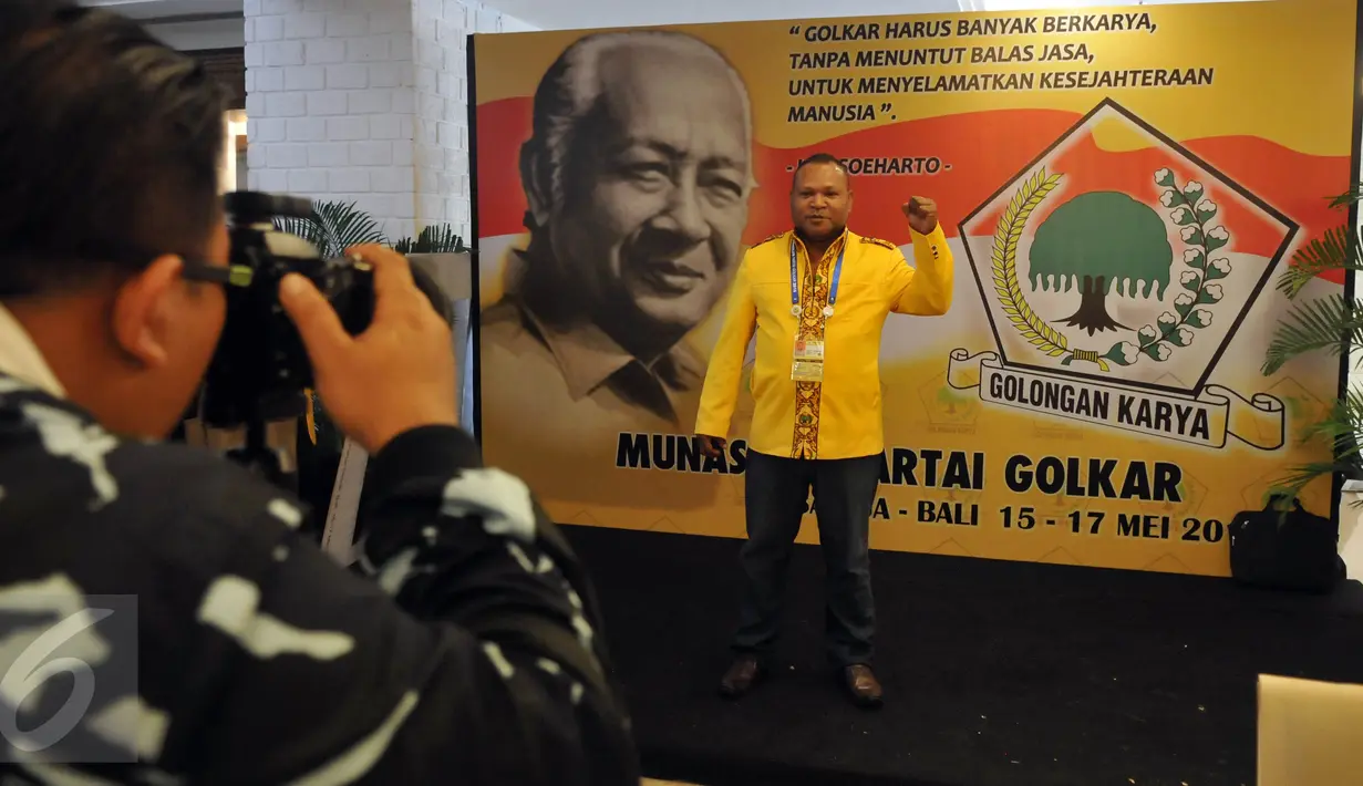 Seorang kader Partai Golkar berpose di depan backdrop Presiden kedua Indonesia, Soeharto disela acara Musyawarah Nasional Luar Biasa (Munaslub) Partai Golkar di Bali Nusa Dua Convention Center (BNDCC), Bali, Minggu (15/5). (Liputan6.com/Johan Tallo)