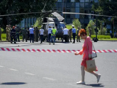 Prajurit berjalan dengan helikopter Black Hawk militer AS setelah mendarat darurat di boulevard yang sibuk, di Bucharest, Rumania, Kamis (15/7/2201). Pendaratan itu merusak dua mobil setelah merobohkan dua tiang lampu namun tidak ada korban yang dilaporkan. (AP Photo/Andreea Alexandru)