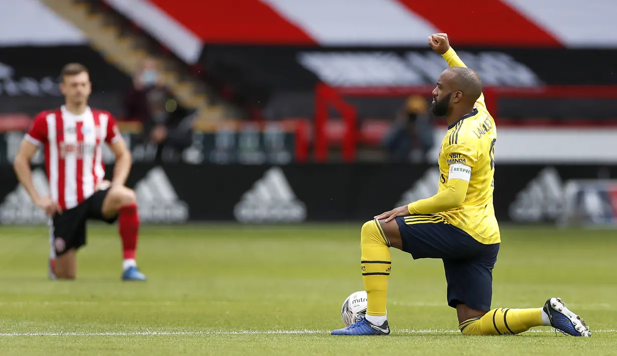 Pemain Arsenal Alexandre Lacazette (kanan) mengacungkan kepalan tangannya saat berlutut sebelum pertandingan menghadapi Sheffield United pada putaran keenam Piala FA di Bramall Lane, Sheffield, Inggris, Minggu (28/6/2020). Arsenal menaklukkan Sheffield United 2-1. (Andrew Boyers/Pool via AP)