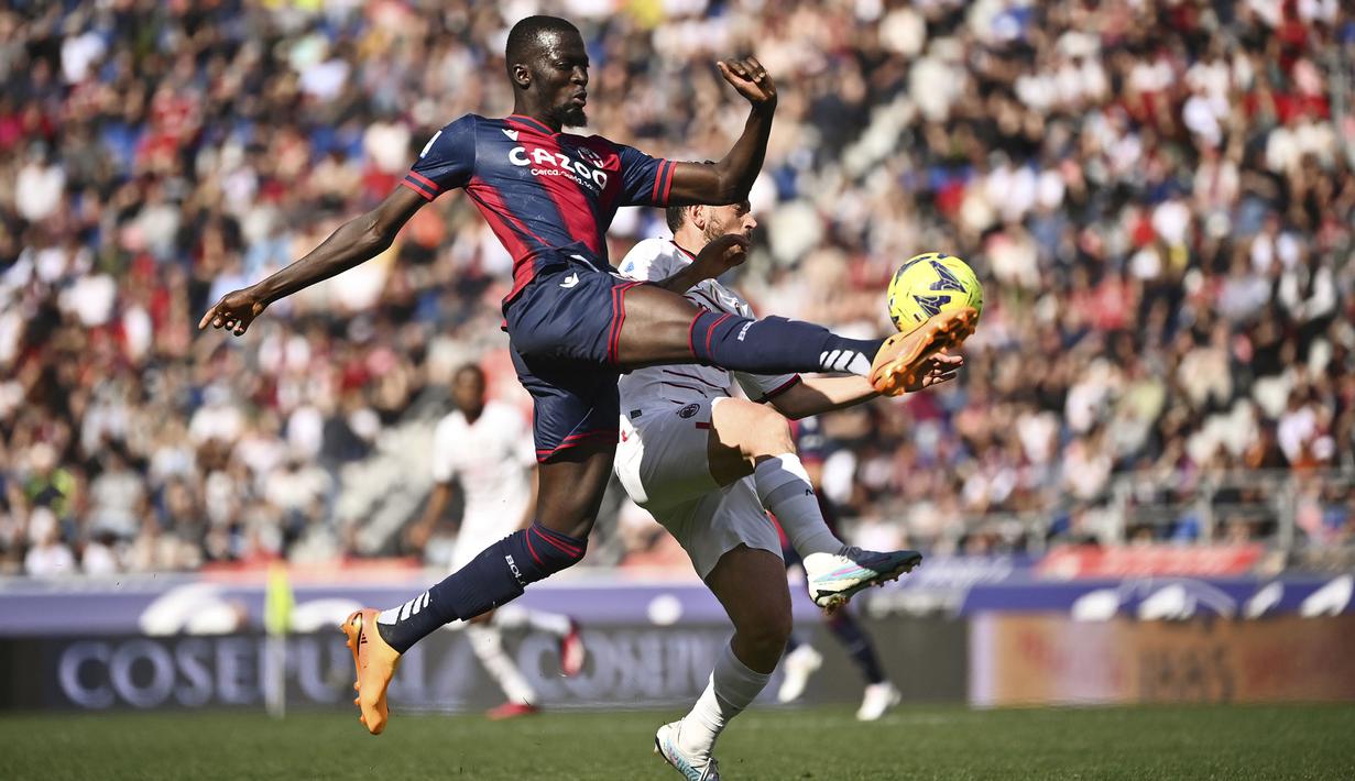 Pemain Bologna, Musa Barrow (kiri) berebut bola dengan pemain AC Milan, Alessandro Florenzi pada laga lanjutan Liga Italia 2022/2023 di Renato-Dall'Ara Stadium, Bologna, Minggu (16/04/2023) WIB. Laga berakhir dengan skor imbang 1-1. (AP Photo/LaPresse/Massimo Paolone)