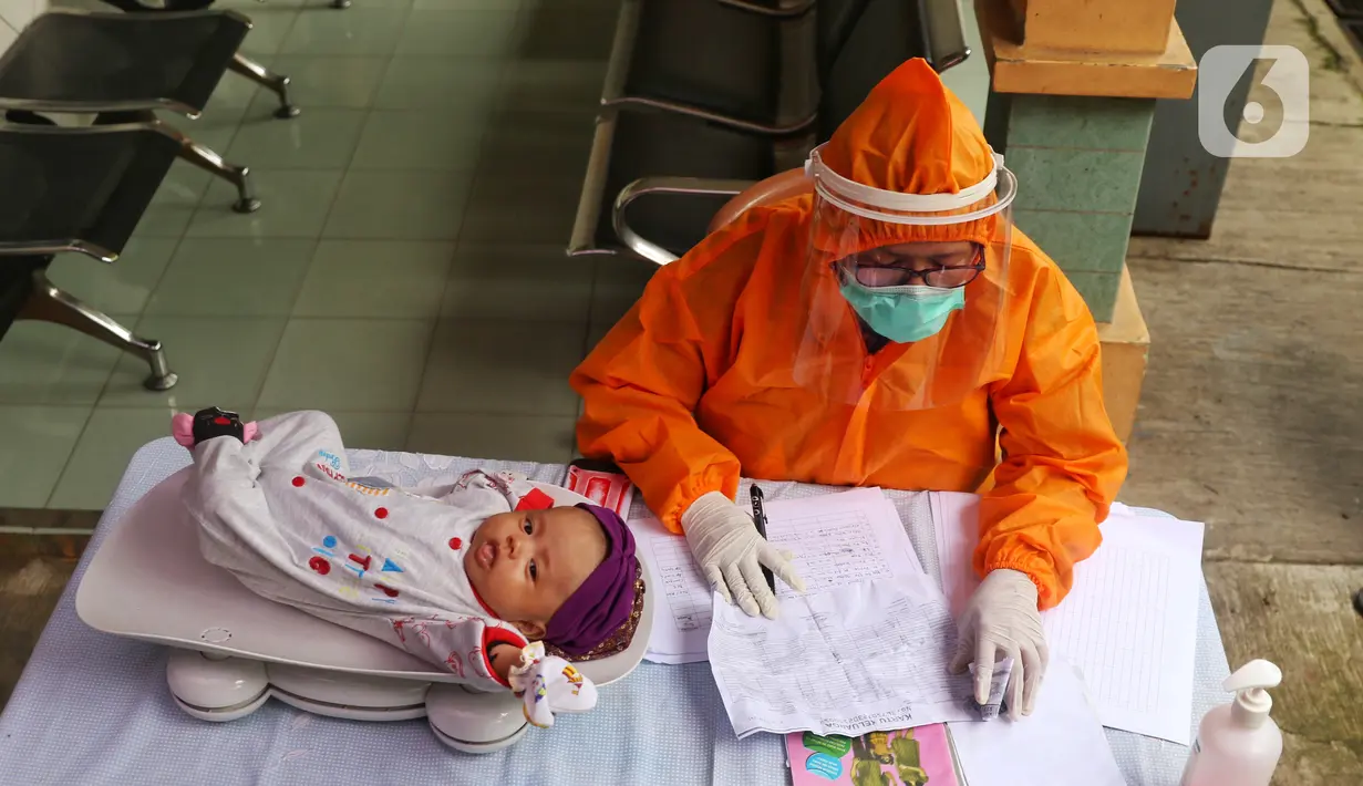 Bidan mengenakan alat pelindung diri (APD) saat melakukan imunisasi kepada bayi di Puskesmas Karawaci Baru, Tangerang, Banten, Rabu (13/5/2020). Pelayanan imunisai sesuai jadwal ini diberikan kepada bayi untuk menambah kekebalan imun tubuh. (Liputan6.com/Angga Yuniar)