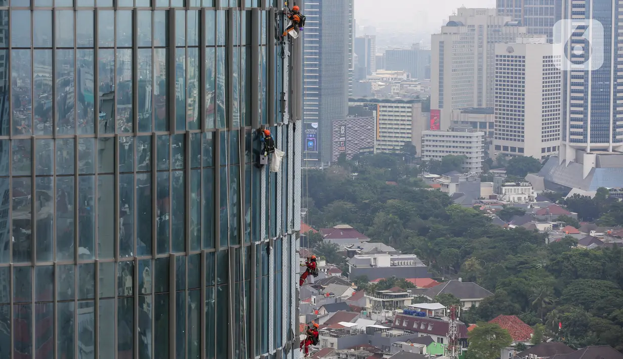 Pekerja membersihkan kaca gedung bertingkat di Jakarta, Jumat (26/02/2021). BP Jamsostek menekankan dua aspek penting terkait pandemi Covid-19, yakni isu kesehatan dan perekonomian dengan jaminan sosial bagi para pekerja dan penerapan K3. (Liputan6.com/Fery Pradolo)