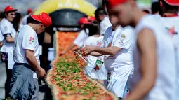 Sejumlah koki ahli berupaya mencetak rekor dunia dengan membuat pizza terpanjang di dunia, di sepanjang pinggir Laut Naples, Italia, 18 Mei 2016. Proses pembuatan pizza membutuhkan waktu sekira 11 jam dan 100 orang koki profesional. (Mario LAPORTA/AFP)