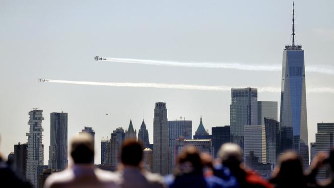 Warga menyaksikan skuadron jet tempur Blue Angels dari Angkatan Laut dan Thunderbirds dari Angkatan Udara Amerika Serikat bermanuver di langit Kota New York, Selasa (28/4/2020). Aksi itu sebagai bentuk penghormatan untuk petugas medis yang tengah berjuang melawan COVID-19. (AP Photo/Seth Wenig)