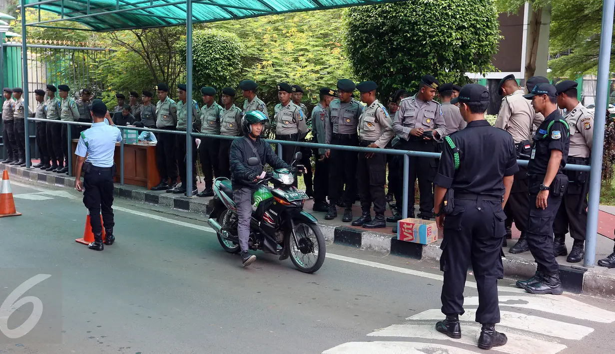 Pengendara motor melintas dekat sejumlah aparat kepolisian yang berjaga di pintu masuk Gedung MPR/DPR RI, Senayan, Jakarta, Jumat (31/3). Polda Metro Jaya memberikan pengamanan ketat di sekitar DPR terkait aksi 31 Maret. (Liputan6.com/Johan Tallo)