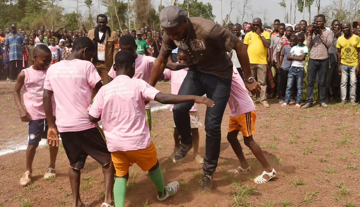 Mantan penyerang Chelsea, Didier Drogba bermain bola dengan murid-murid saat peresmian sekolah yang disponsori dirinya di Pokou-Kouamekro, dekat Gagnoa, Pantai Gading tengah barat (17/1). (AFP Photo/Sia Kambou)