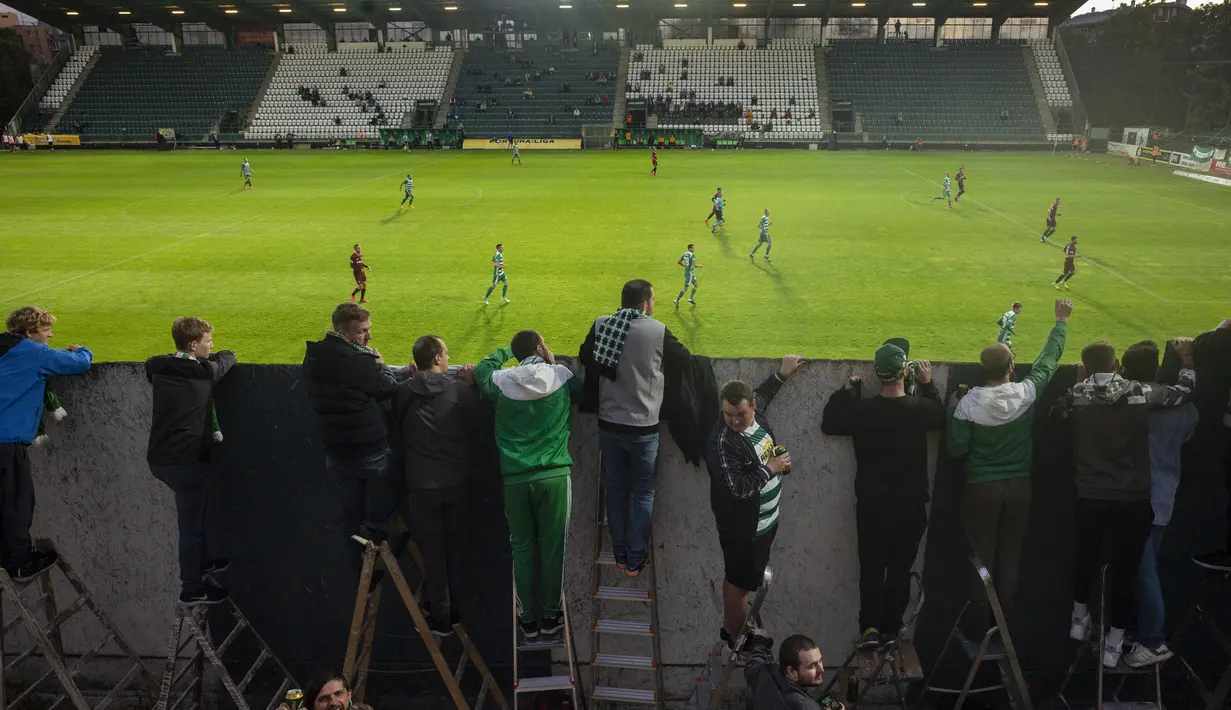 Suporter Bohemians 1905 menyaksikan pertandingan melawan Sparta Praha pada laga Liga Fortuna di Praha, Rep. Ceko (6/6/2020). Laga tertutup karena pembatasan virus corona tersebut membuat fans menonton dari balik tembok. (AFP/Michal Cizek)