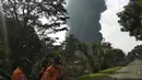 Petugas penyelamat berdiri saat asap tebal mengepul dari api yang melanda Kilang Pertamina Balongan di Indramayu, Jawa Barat, Indonesia, Senin (29/3/2021). Ratusan orang yang tinggal di desa-desa sekitar kilang telah dievakuasi menyusul kebakaran yang terjadi setelah kebakaran. (AP Photo)
