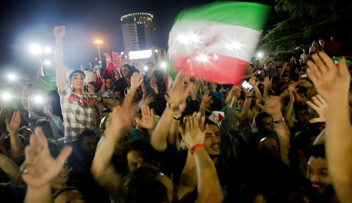 Warga Iran turun ke jalan merayakan lolosnya timnas kesayangan mereka ke Piala Dunia 2018 Rusia, Senin (12/6). Sukses Iran tersebut diraih setelah mengalahkan Uzbekistan dengan skor 2-0 dalam kualifikasi Grup A zona Asia. (AP Photo/Ebrahim Noroozi)