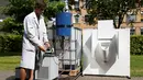Ilmuwan Belgia, Sebastiaan Derese menuangkan air dari mesin buatannya yang bisa mengubah air seni menjadi air yang layak diminum dan menjadi pupuk dengan bantuan energi matahari, di University of Ghent, Belgia, Selasa (26/7). (REUTERS/Francois Lenoir)