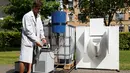 Ilmuwan Belgia, Sebastiaan Derese menuangkan air dari mesin buatannya yang bisa mengubah air seni menjadi air yang layak diminum dan menjadi pupuk dengan bantuan energi matahari, di University of Ghent, Belgia, Selasa (26/7). (REUTERS/Francois Lenoir)