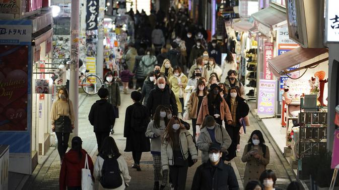 Orang-orang memakai masker untuk mencegah penyebaran virus corona berjalan di pusat perbelanjaan di Tokyo (9/2/2021). Jepang telah memberlakukan UU yang memungkinkan pejabat untuk menegakkan tindakan virus corona dengan menghukum pelanggar perintah wajib dengan denda. (AP Photo/Eugene Hoshiko)
