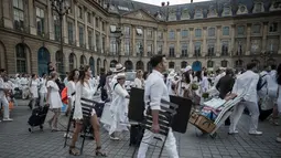 Peserta membawa kursi dan perlengkapan lain ketika mengikuti 'Diner en blanc' atau 'Makan Malam Putih' di Place Vendome, Paris, Rabu (8/6). Untuk  mendapatkan undangan, peserta harus mengenal seorang anggota organisasi Diner en Blanc. (PHILIPPE LOPE/AFP)