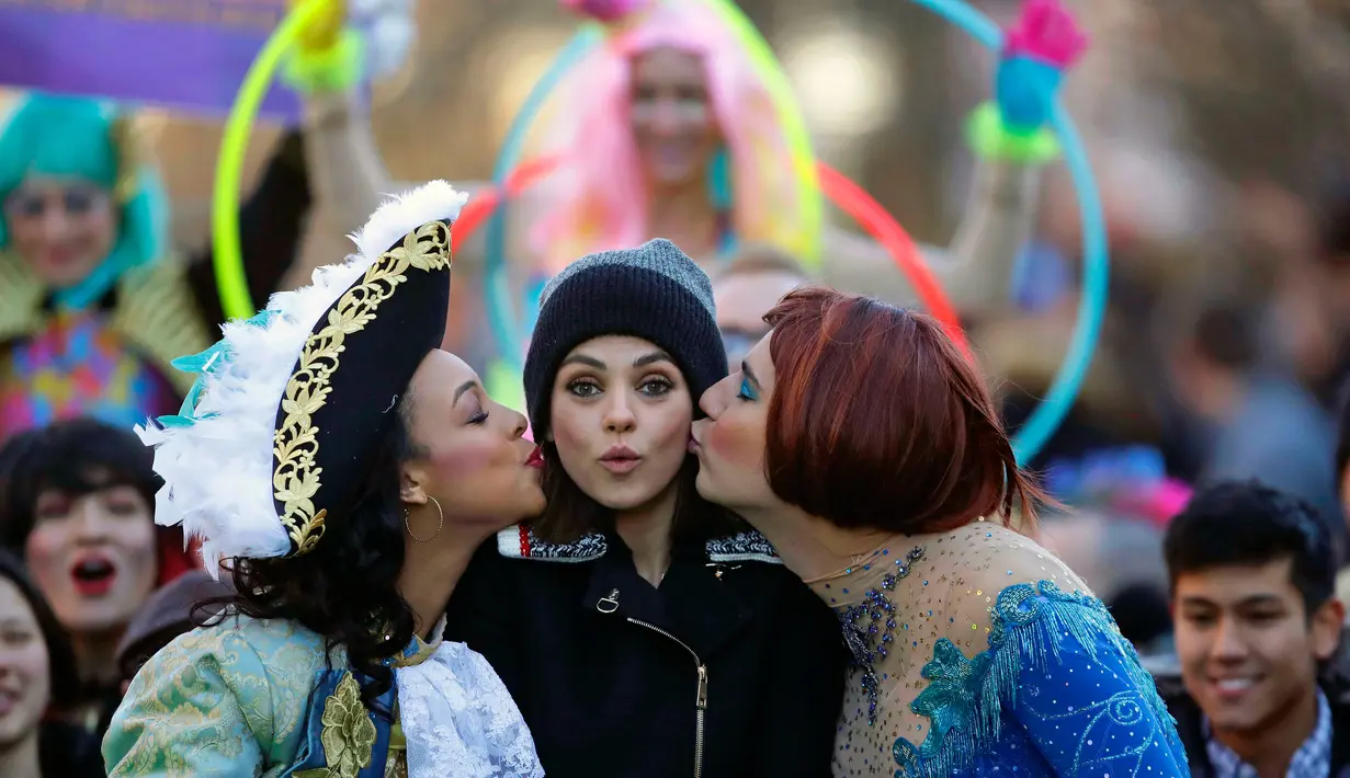 Aktris Mila Kunis (tengah) dicium oleh Amira Weeks (kiri) dan Jacques Berguig dalam sebuah parade di Cambridge (25/1). Mila Kunis dinobatkan sebagai "Woman of the Year" oleh kelompok teater Hasty Pudding. (AP Photo / Charles Krupa)