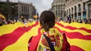 Seorang wanita mengenakan bendera Spanyol di bahunya ketika orang-orang mengarak bendera Catalonia berukuran raksasa pada perayaan Dia de la Hispanidad  di jalanan Barcelona, Kamis (12/10). (AP / Santi Palacios)