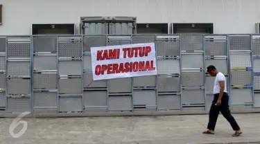 Warga melewati di spanduk 'Kami Tutup Operasional' di pabrik pengolahan ikan Pelabuhan Muara Baru, Jakarta, Senin (10/10). Mogok massal karena dibatasinya masa sewa di pelabuhan selama 5 tahun yang tadinya selama 20 tahun.  (Liputan6.com/Gempur M Surya)