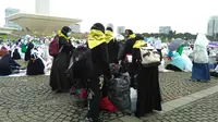 Satgas GNPF-MUI memungut sampah yang ditinggalkan peserta aksi damai 212 di Monas, Jakarta Pusat. (Liputan6.com/Seysha Desnikia)