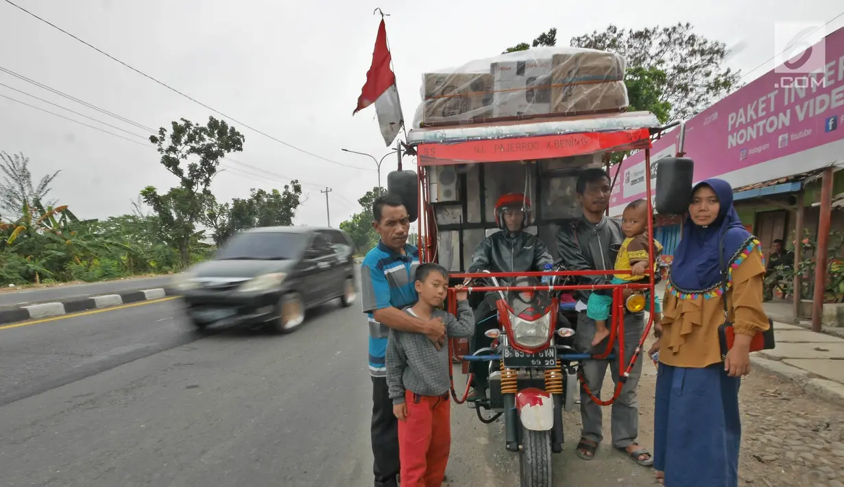 Pemudik bersama keluarganya menggunakan motor bak roda tiga bersiap melakukan perjalanan mudik di Jalur Pantura kawasan Pemalang, Jateng, Senin (3/6/2019). Motor bak roda tiga ini biasanya digunakan untuk mengangkut sampah dari tempatnya bekerja di Rawajati Kalibata. (Liputan6.com/Herman Zakharia)