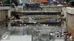 Warga melintasi jembatan kali di Jalan Petojo Utara VI, Jakarta, Senin (26/12). Kali tersebut terlihat kotor akibat ceceran sampah limbah plastik, botol minuman ringan dan sterefoam. (Liputan6.com/Helmi Fithriansyah)