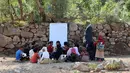 Anak-anak mengikuti kelas terbuka di bawah pohon dekat sekolah mereka yang belum selesai pada tahun ajaran baru di negara yang dilanda perang di desa al-Kashar Yaman barat daya di distrik Mashraa dan Hadnan di provinsi Taez (16/9/2019). (AFP Photo/Ahmad Al-Basha)
