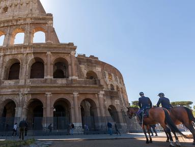 Polisi (kanan) dan petugas Carabinieri berpatroli di luar Colosseum di Roma, Italia, Senin (1/6/2020). Colosseum, yang merupakan ikon kota Roma dibuka kembali untuk umum pada Senin (1/6), setelah ditutup lebih dari dua bulan, dengan beberapa pembatasan akses bagi pengunjung. (AP/Domenico Stinellis)