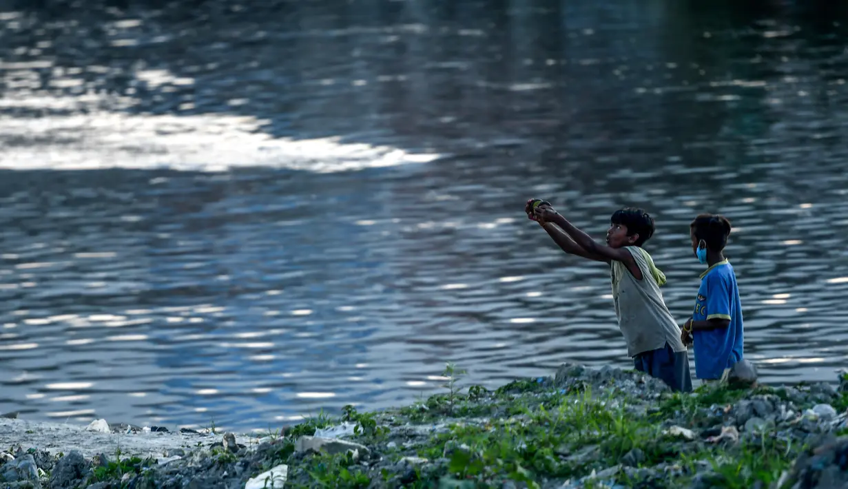 Anak laki-laki menerbangkan layang-layang di tepi sungai menjelang festival Hindu Dashain di Kathmandu (7/10/2020). Festival ini yang paling dinantikan di Nepal, Bhutan, Burma, dan perbukitan India Utara. (AFP/Prakash Mathema)