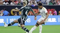 Pemain Real Madrid, Jude Bellingham (kanan), menendang bola dan dihadang pemain MU, Lisandro Martinez (kiri), dalam pertandingan pramusim Soccer Champions Tour 2023 yang berlangsung di NRG Stadium, Houston, Kamis (27/7/23). Kedua pemain tersebut terlibat keributan di menit ke-42 setelah Martinez melakukan pelanggaran keras berupa tekel dengan kedua kakinya terhadap Jude Bellingham. (AP Photo/Michael Wyke)