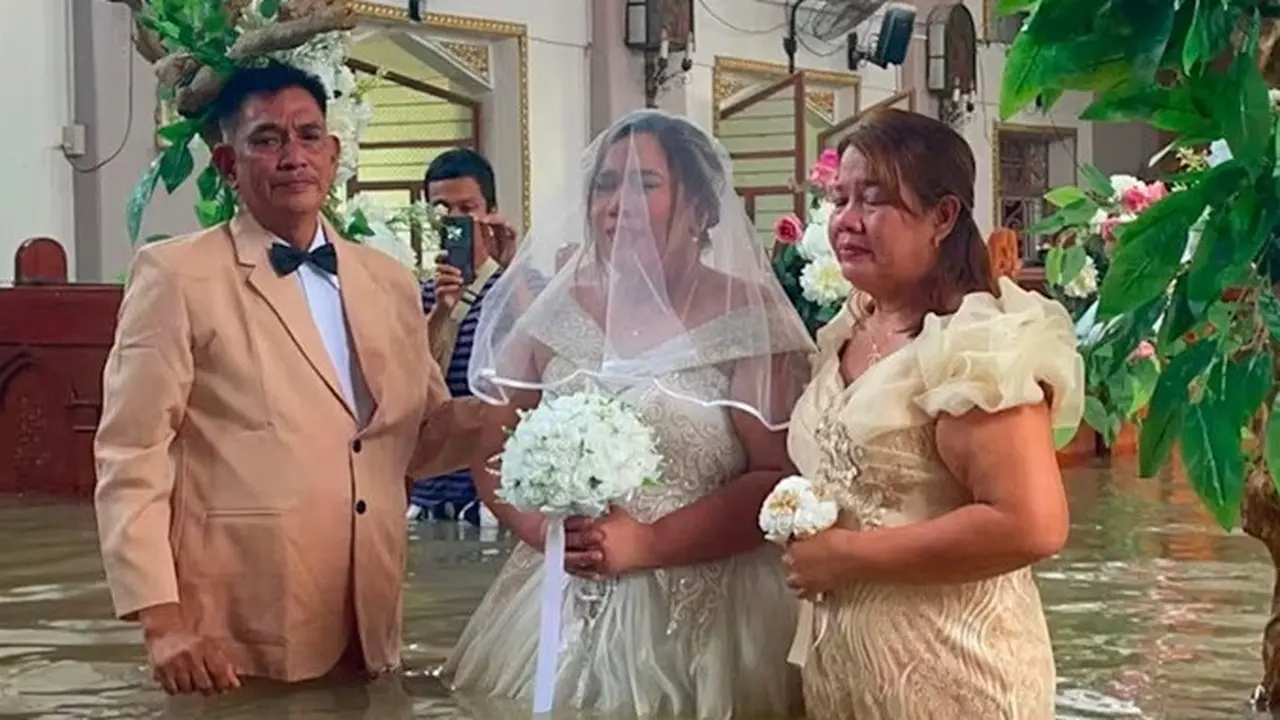 Leian Lieza Galang berjalan menerobos banjir berwarna cokelat keruh di dalam Gereja Saint John the Baptist di Hagonoy, sebelah utara Manila, pada 1 September 2026.