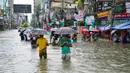 Orang-orang membawa payung menyeberangi jalan yang tergenang air di tengah curah hujan di Feni, Bangladesh pada Kamis 22 Agustus 2024. (Foto oleh AFP)