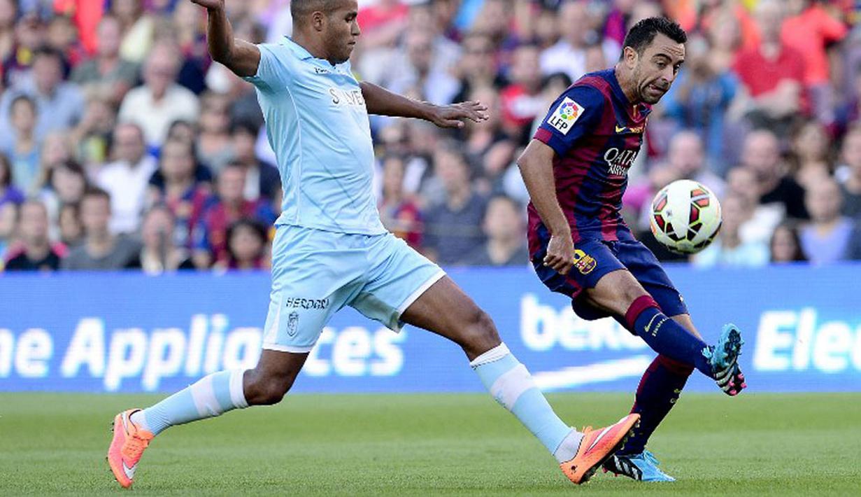 Gelandang Barcelona, Xavi Hernandez (kanan), mencoba melewati hadangan Youssef El-Arabi (Granada) saat berlaga di lanjutan La Liga 2014 di Stadion Camp Nou, (27/9/2014). Barcelona unggul enam gol tanpa balas atas Granada. (AFP PHOTO/Josep Lago)