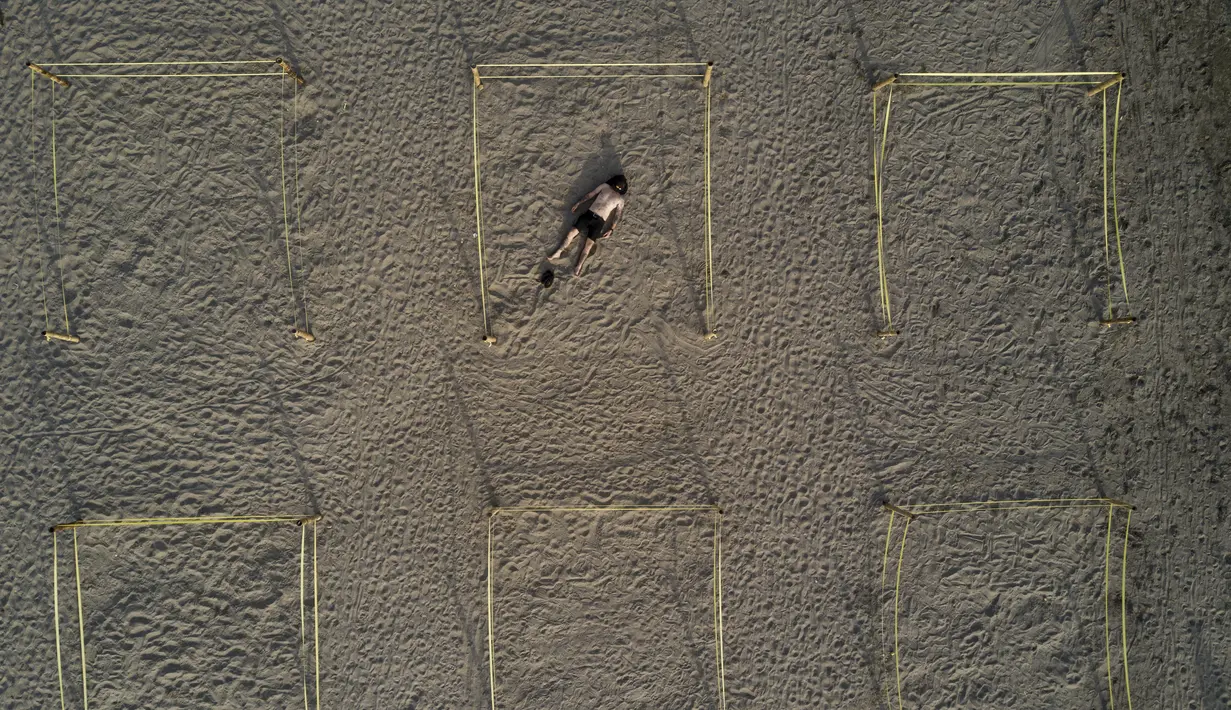 Seorang pria berjemur dalam pembatas untuk menghindari keramaian di tengah pandemi COVID-19 di Pantai Lima, Peru, Rabu (21/12/2021). Di pantai-pantai populer di Lima, pihak berwenang memutuskan membuat pembatas untuk mencegah kerumunan pengunjung. (Ernesto BENAVIDES/AFP)